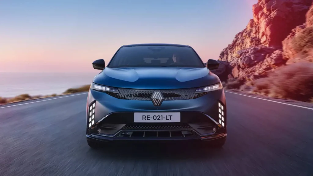 Renault électrique bleue en mouvement sur route côtière, face avant dynamique.