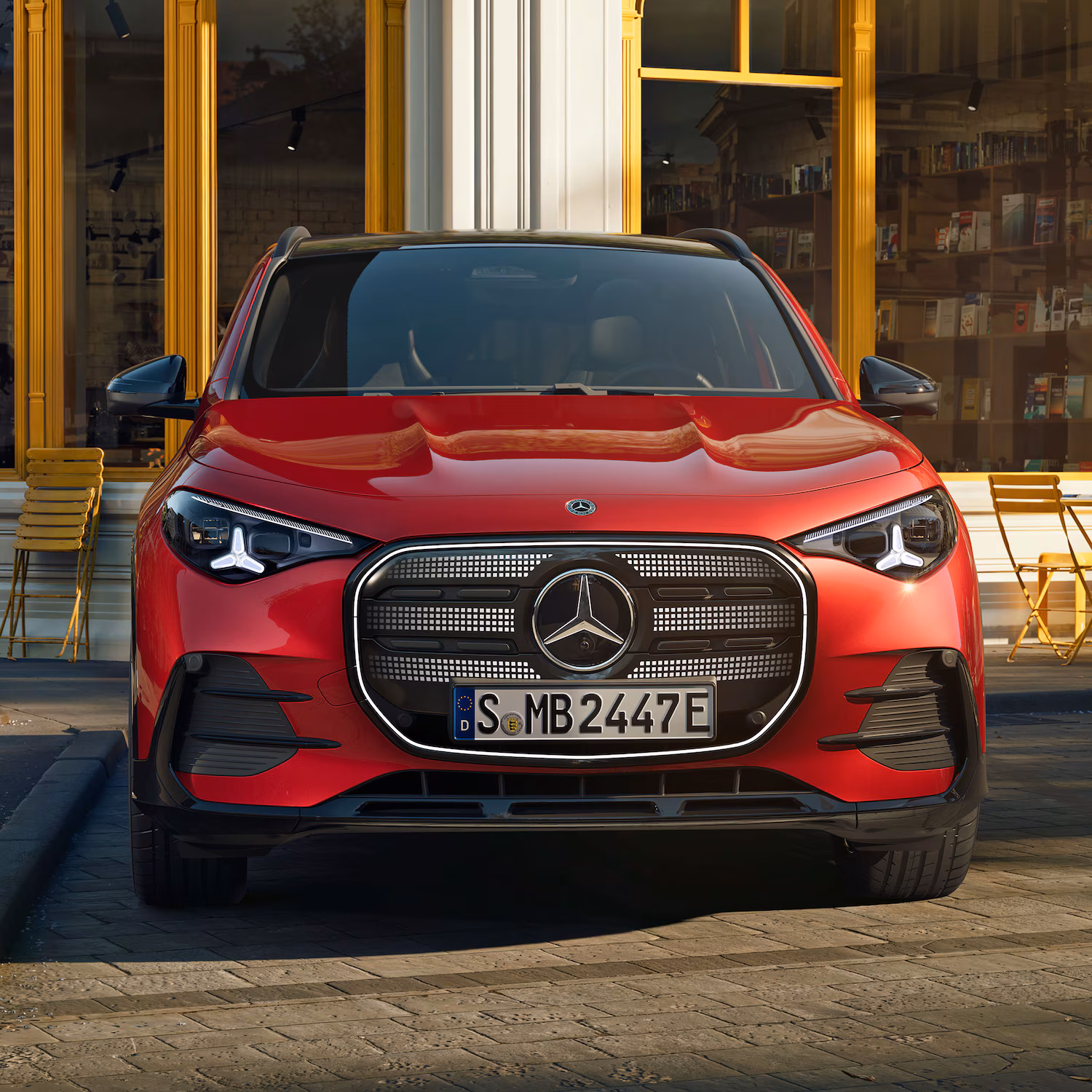 Mercedes électrique rouge vue de face, calandre étoile et signature lumineuse moderne.